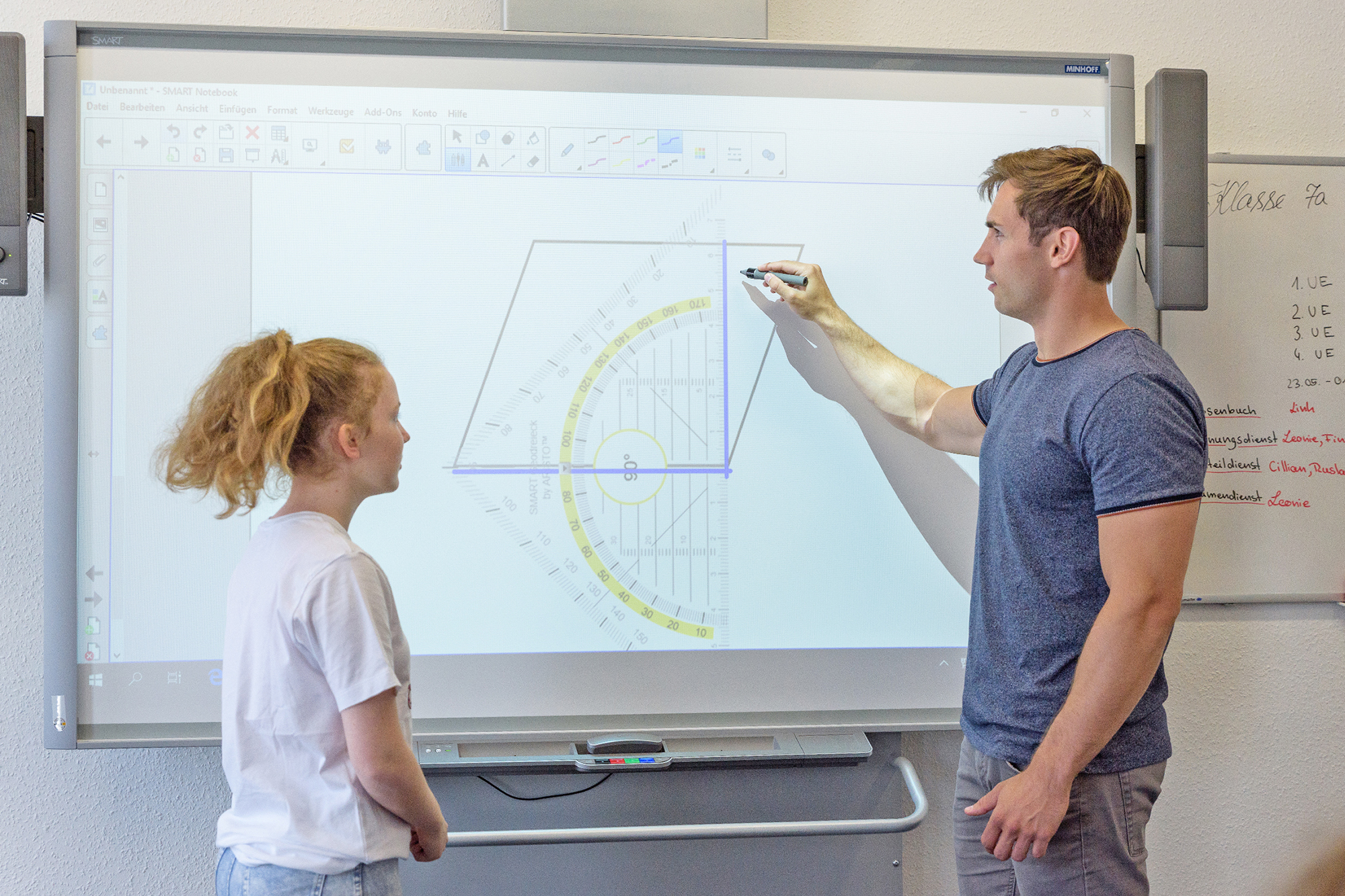 Lehrer und Schülerin im Gespräch am digitalen Smartboard
