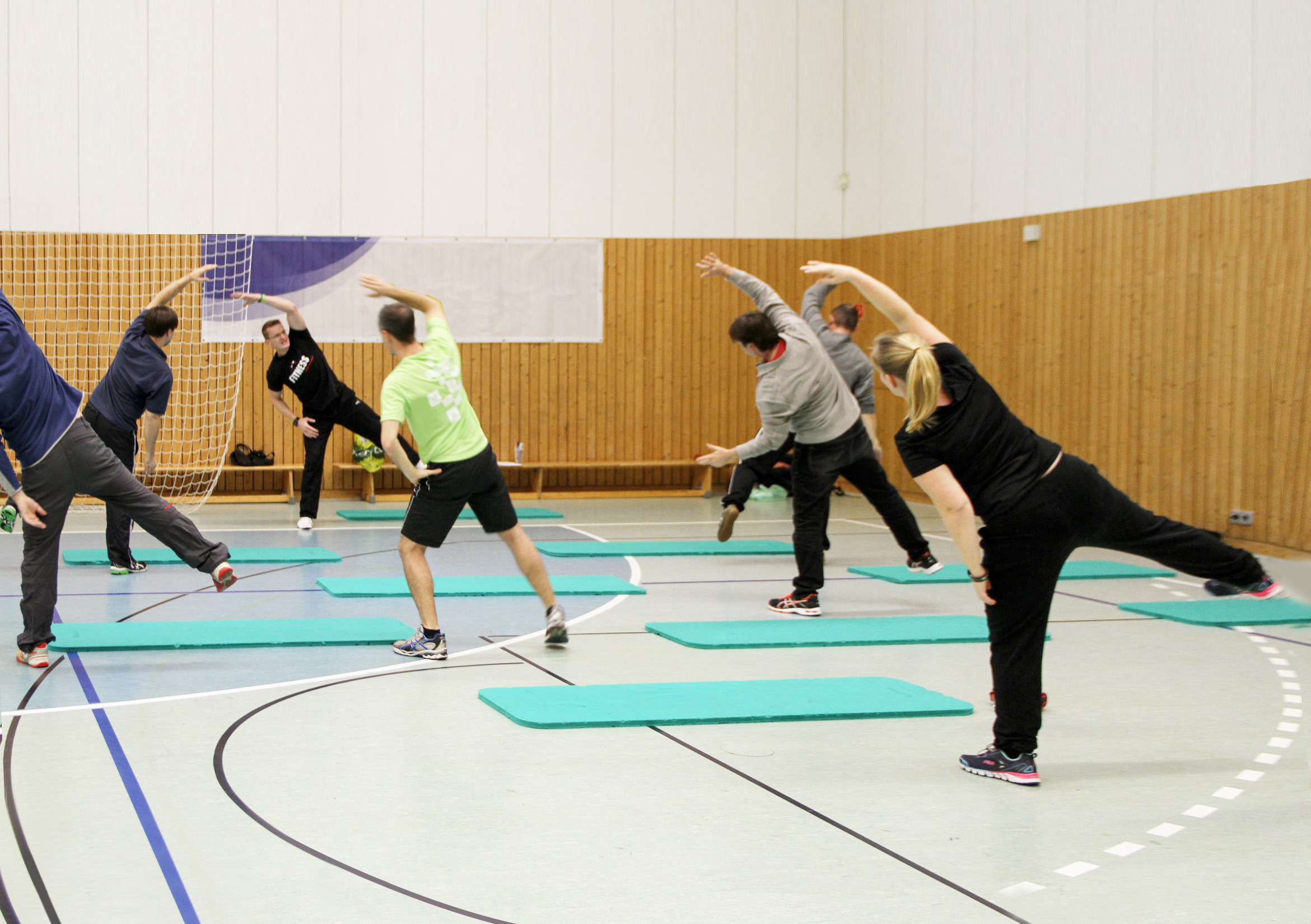 Lehrer bewegen sich unter Anleitung beim Angebot Rückenfit